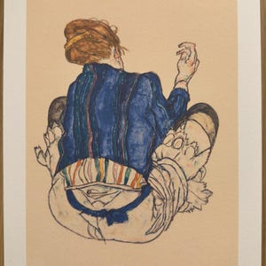 Peut inclure: Une estampe d'une figure assise, vue de dos, avec des cheveux roux et une veste bleue à rayures verticales. La figure porte un pantalon blanc avec un motif rayé coloré à la taille. L'estampe est numérotée 5/80.