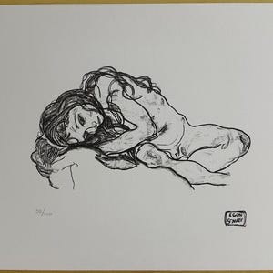 May include: A black and white sketch of a reclining figure with long hair. The artwork is signed and numbered 20/100. The style is reminiscent of a classic drawing, with delicate lines and shading.