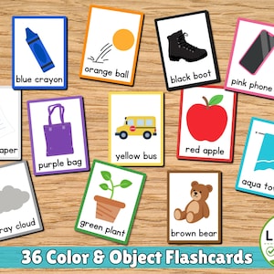 May include: A set of educational flashcards featuring illustrations of a blue crayon, orange ball, black boot, pink phone, white paper, purple bag, yellow bus, red apple, aqua towel, grey cloud, green plant, and brown bear with text labels.