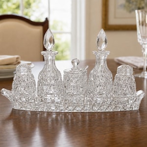 May include: A clear glass condiment set featuring a rectangular tray with a diamond-cut pattern, two cruets with pointed stoppers, two shakers, and a small lidded jar with a spoon, all displaying a matching intricate geometric faceted texture.