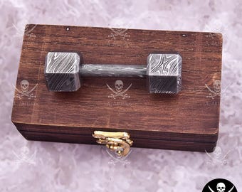 May include: A handcrafted dumbbell with a patterned metal design, resting on a wooden box with a brass clasp. The dumbbell's ends are square, and the handle is cylindrical. The box is made of dark wood.