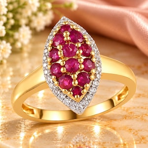 May include: A gold ring featuring a marquise-shaped cluster of round, deep red rubies set in yellow gold prongs, surrounded by a halo of small, clear white diamonds set in a silver-toned metal frame on a polished yellow gold band.