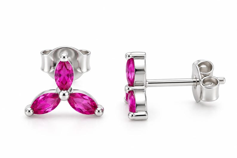May include: A pair of silver stud earrings featuring three marquise-cut vibrant pink stones arranged in a clover-like cluster. Each earring includes a post back mechanism, showcasing a polished metallic finish and faceted gemstone surfaces.