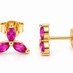 May include: A pair of gold stud earrings, each featuring three marquise-cut vibrant pink stones arranged in a floral cluster pattern. The earrings include gold posts and matching butterfly-style friction backs for secure attachment to the earlobe.