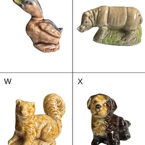 May include: A collection of four small ceramic animal figurines. Includes a duck, a rhinoceros, a squirrel, and a puppy. The duck is brown and gray, the rhino is tan, the squirrel is tan and orange, and the puppy is brown and tan.