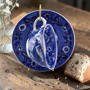 May include: A set of three ceramic mugs with a speckled, matte finish. The mugs are in shades of cream, light gray, and dark gray. Each mug has a simple, minimalist design and a rounded handle.