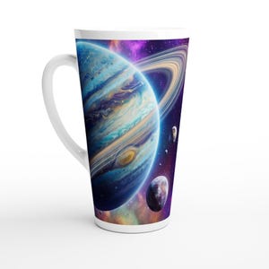 Peut inclure: Un grand mug en céramique blanche orné d'une impression enveloppante représentant une géante gazeuse avec des anneaux visibles, entourée de petites lunes sur un fond de nébuleuse spatiale aux teintes violettes, bleues et orangées.