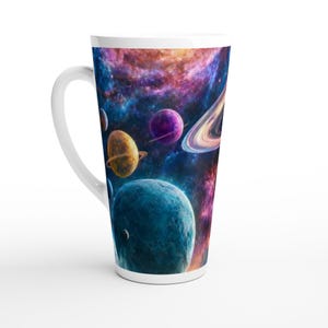 Op de afbeelding: Een witte keramische latte mok met een rondom lopende print van de ruimte. Het ontwerp toont meerdere planeten, waaronder een met opvallende ringen, tegen een kleurrijke nevelachtergrond in diepe blauwe, paarse en oranje tinten.