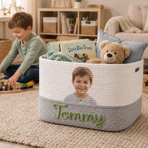 May include: A rectangular white and gray woven rope storage basket featuring a custom photo of a young boy printed on the front and the name Tommy embroidered in green yarn on the lower gray section, with integrated side handles for carrying.