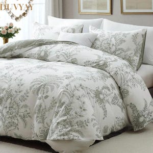 May include: White and gray floral patterned bedding set. The set includes a duvet cover and pillowcases. The duvet cover features a large-scale floral design in shades of gray on a white background. The pillowcases have a matching pattern.