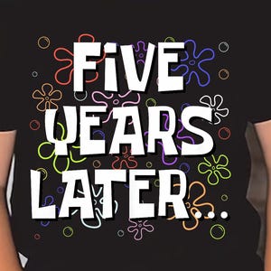 Op de afbeelding: Een zwart t-shirt met de tekst "FIVE YEARS LATER" in het wit, met kleurrijke bloemenafbeeldingen. Het shirt wordt gedragen door een kind met een zwarte zonnebril.