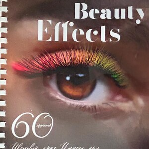 May include: A book titled "Lash Beauty Effects" with a close-up of an eye with rainbow-coloured eyelashes. The lashes transition from red to yellow-green. The book cover includes text and the number 60. The book is spiral-bound.