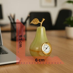 Könnte beinhalten: Eine birnenförmige dekorative Uhr, 9,5 cm hoch und 6 cm breit, mit goldenem Blatt- und Stieldetail. Das Zifferblatt ist weiß mit schwarzen Ziffern und Zeigern, in einem goldenen Rahmen. Der Körper ist hellgrün.
