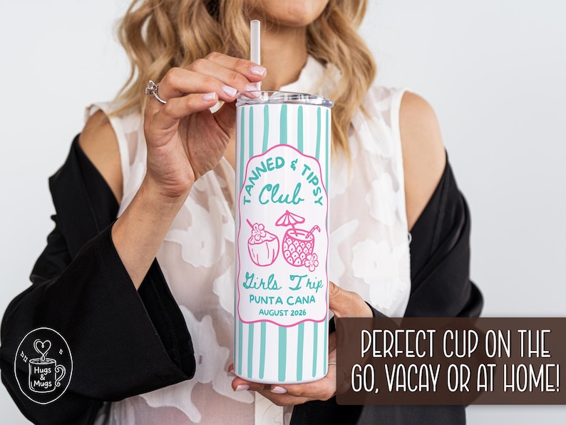 May include: A white and teal striped tumbler with a lid and straw. The tumbler has a pink label that reads "Tanned & Tipsy Club Girls Trip Punta Cana August 2026". The tumbler is held by a person.