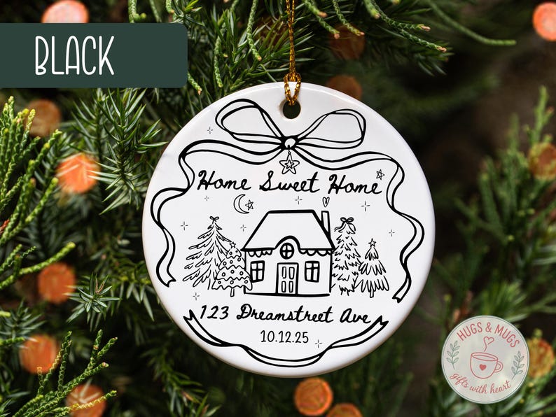 May include: White ceramic Christmas ornament with a black line drawing of a house, trees, and the text "Home Sweet Home." Includes the address "123 Dreamstreet Ave" and the date "10.12.25." A black banner at the top reads "BLACK."