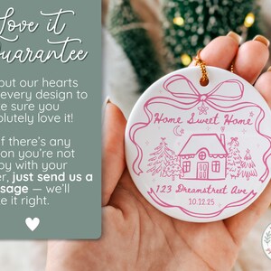 May include: A white ceramic Christmas ornament with a pink illustration of a house, trees, and the words "Home Sweet Home." The ornament also includes the address "123 Dreamstreet Ave" and the date "10.12.25."