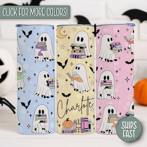 May include: Three Halloween-themed tumblers with ghost illustrations holding books. The tumblers feature light blue, yellow, and pink backgrounds with bats, stars, and a pumpkin. One tumbler has the name "Charlotte" on it.