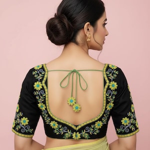 Peut inclure: Un chemisier noir brodé avec des détails floraux jaunes et bleus. Le chemisier présente une encolure carrée et des manches courtes. La broderie est soulignée de jaune et de vert. Le dos a une fermeture à nouer verte.