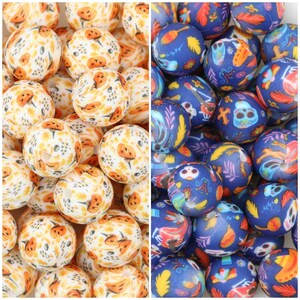 Peut inclure: Une collection de perles sphériques divisées en deux groupes. Le côté gauche présente des perles blanches avec des motifs de citrouilles et de feuilles orange. Le côté droit présente des perles bleu foncé avec des motifs de crânes et de fleurs.