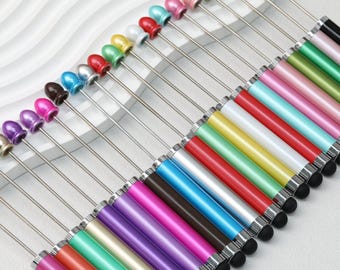 May include: An assortment of colorful stylus pens. Each pen has a metallic silver shaft, a colored barrel, and a black tip. The tops of the pens are adorned with various colored beads, including pink, green, blue, and brown.