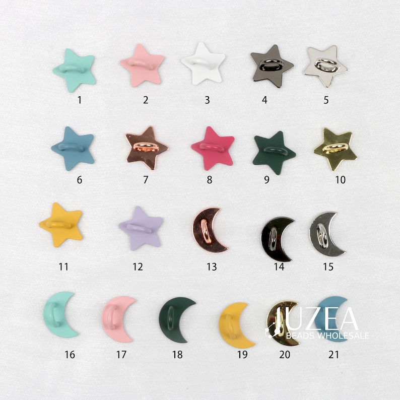 Puede incluir: Una colecci&oacute;n de botones met&aacute;licos en forma de estrella y media luna en varios colores, incluyendo azul, rosa, blanco y dorado. Los botones est&aacute;n dispuestos sobre una superficie blanca, cada uno numerado.
