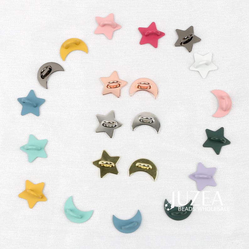 Puede incluir: Un surtido de abalorios met&aacute;licos en forma de estrella y media luna de colores. Los abalorios son de varios colores, incluyendo rosa, dorado, plateado, azul y verde. Los abalorios est&aacute;n dispuestos sobre una superficie blanca. El texto "JUZEA BEADS WHOLESALE" es visible.