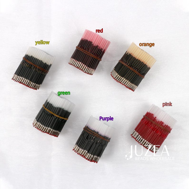 May include: An overhead shot displays six bundles of beads in various colors: yellow, red, orange, green, purple, and pink. Each bundle is secured with a brown rubber band. The image includes the text "JUZEA BEADS WHOLESALE".