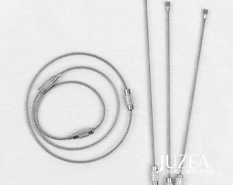 Puede incluir: Una colección de cordones y alambres de joyería de color plateado. Algunos están enrollados, mientras que otros son rectos con extremos decorativos. La imagen incluye el texto "JUZEA BEADS WHOLESALE".