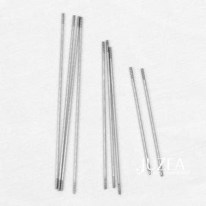 Könnte beinhalten: Eine Ansammlung silberfarbener Stecknadeln mit strukturierten Enden, angeordnet auf einer weißen Oberfläche. Die Stifte variieren in der Anzahl und sind für Bastelarbeiten oder die Schmuckherstellung bestimmt. Das Bild ist gut beleuchtet und hebt den metallischen Glanz der Stifte hervor.