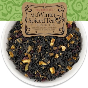May include: A close-up of a bowl of loose leaf black tea blend called "Mid Winter Spiced Tea" by Dem Bones Tea. The tea blend contains dried orange peel, cinnamon, hibiscus, and elderflower.