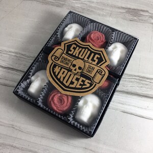 Tile background with box of skull shaped sugar cubes and red rose shaped sugar cubes, each sugar cube sits in a candy cup in a grid, Kraft labels read: Skulls N Roses, DemBones Original, Sugar Cubes