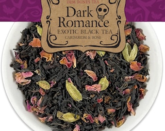 Op de afbeelding: Een close-up van een kom met losse zwarte thee met rozenblaadjes en kardemompeulen. De thee is geëtiketteerd met "Dark Romance Exotic Black Tea Cardamom & Rose" door Dem Bones Tea.