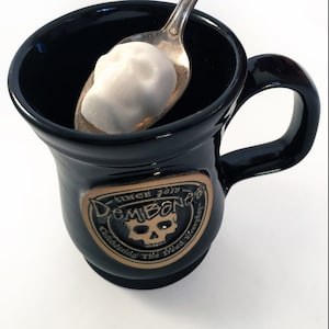 DemBones logo mug with skull sugar cube on silver spoon, white background,