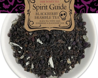 Op de afbeelding: Een witte kom gevuld met losse zwarte theebladeren. De thee is een mix van zwarte thee, witte salie, vlierbes en braambesbladeren. Het etiket op de kom luidt "Dem Bones Tea Spirit Guide Blackberry Bramble Tea Black Tea, White Sage, Elderberry & Blackberry Leaf."