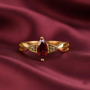 Elegante anello in oro con granato rosso marquise e accenti di diamanti