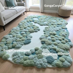 Puede incluir: Una alfombra grande, de forma irregular, con un dise&ntilde;o de bosque. La alfombra presenta un camino blanco en forma de r&iacute;o rodeado de &aacute;reas afelpadas y texturizadas en tonos verdes y azules. La alfombra est&aacute; colocada sobre un suelo de madera noble.