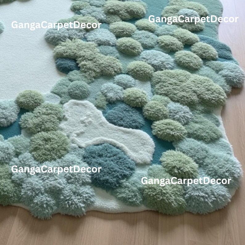 Puede incluir: Una alfombra tupida con dise&ntilde;o de paisaje. La alfombra presenta una mezcla de texturas y colores, incluyendo tonos de verde, azul y blanco, creando un efecto tridimensional. El texto "GangaCarpetDecor" es visible en varios lugares.