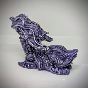 May include: A detailed, purple and silver sculpture with an intricate, biomechanical design. The artwork features a complex arrangement of organic and mechanical elements, creating a unique, otherworldly aesthetic. The sculpture is set against a plain white background.