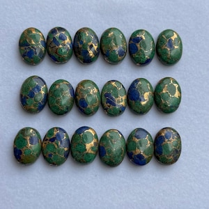 May include: Sixteen oval-shaped gemstones with a green, blue, and gold color scheme. The gemstones are arranged in three rows, each with five or six stones. The stones have a speckled appearance.