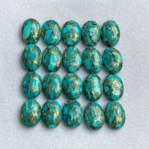 Puede incluir: Dieciséis piedras preciosas ovaladas de color turquesa con vetas doradas. Las piedras están dispuestas en cuatro filas de cuatro, cada una con una superficie pulida. Las piedras preciosas tienen un aspecto brillante. Cada piedra mide unos 2 cm de largo.