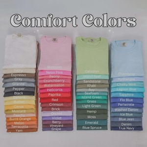 May include: A display of Comfort Colors t-shirts in a range of shades, from white and pink to green and blue. Each stack of folded shirts is labelled with a colour name, like "Blossom" and "Chambray".