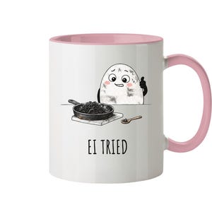 Könnte beinhalten: Weiße Keramik-Tasse mit rosa Innenraum und Henkel. Die Tasse zeigt eine Cartoon-Ei-Figur mit einem Daumen hoch, eine Pfanne mit schwarzem Essen und den Text "EI TRIED".