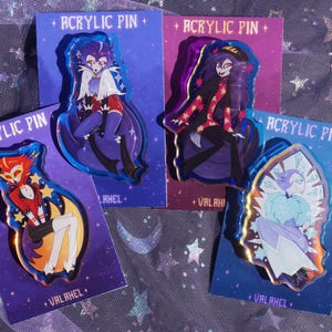 Può includere: Quattro spille in acrilico con personaggi dei cartoni animati colorati su biglietti viola. Ogni spilla ha un design unico, con la scritta "ACRYLIC PIN" in alto. I biglietti hanno la scritta "VALAHEL" in basso.