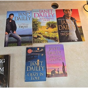 May include: A collection of Janet Dailey novels, including "Trust," "Something More," "Triumph," "Crazy in Love," and "Sunrise Canyon." The book covers feature images of people and landscapes, with titles in bold font.