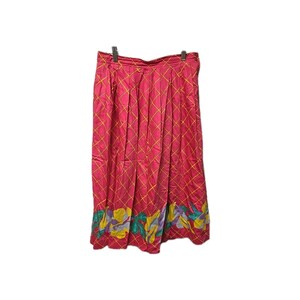 May include: A pleated midi skirt in a vibrant magenta pink featuring a yellow grid pattern throughout. The hemline is decorated with a colorful floral print in shades of yellow, teal, and purple. The skirt is suspended from a metal hanger.