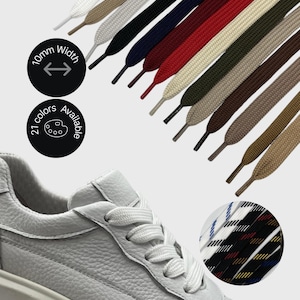 Puede incluir: Se muestra una zapatilla de cuero blanco con cordones blancos. Arriba, se exhiben una variedad de cordones planos en varios colores, incluyendo blanco, negro, azul marino y rojo. El texto indica que los cordones tienen 10 mm de ancho y están disponibles en 21 colores.