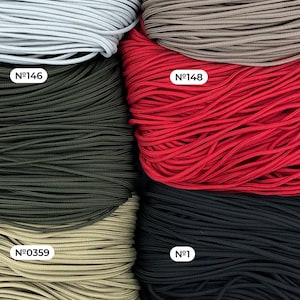 May include: Close-up of several spools of cord in various colors. The colors include gray, brown, red, black, olive green, and tan. Each spool is labeled with a number. The cords are tightly wound and appear to be made of a smooth, durable material.
