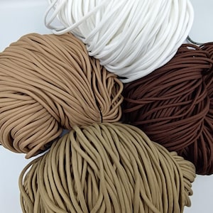 May include: A selection of tightly wound cords in shades of white, beige, light brown, tan, and dark brown. The image shows several bundles of cord, suitable for crafts or other creative applications.