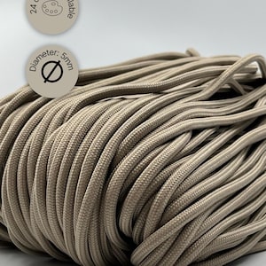 Puede incluir: Un rollo de cuerda beige. La cuerda tiene un diámetro de 5 mm. La imagen incluye dos gráficos circulares, uno que indica "24 colores disponibles" y otro que indica "Diámetro: 5 mm".