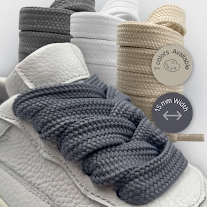 May include: A white leather trainer with grey shoelaces. The image displays stacks of shoelaces in grey, white, and beige. Text on the image indicates 7 colours are available and the laces are 15 mm wide.